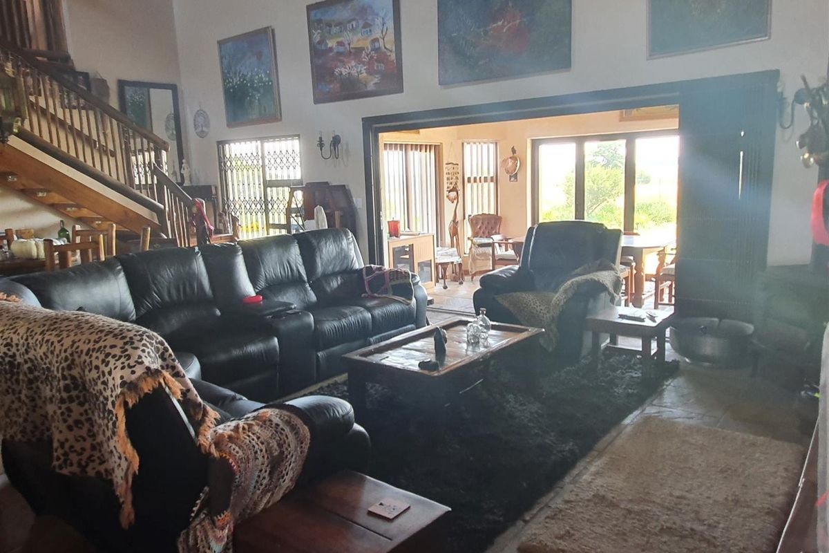 Spacious living room featuring stone flooring, a wooden staircase, and large sliding glass doors that provide access to the outdoor area.