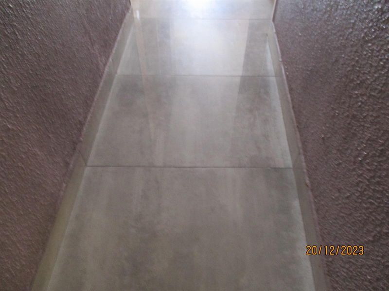 A narrow hallway featuring textured wall finishes and large format floor tiles.