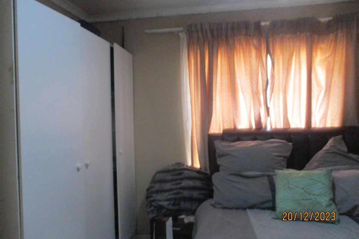 A bedroom featuring built-in white cabinetry and a window with curtains.