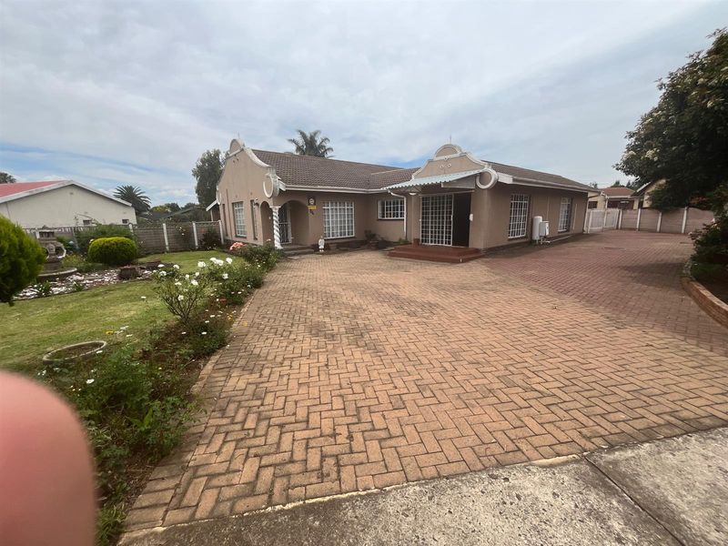A single-story residential property featuring a paved driveway, landscaped front garden, and traditional architectural detailing with a tiled roof.