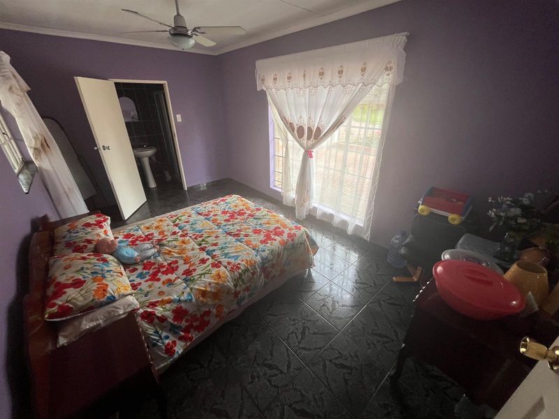 A bedroom featuring dark tiled flooring, a ceiling fan, and an en-suite bathroom access.