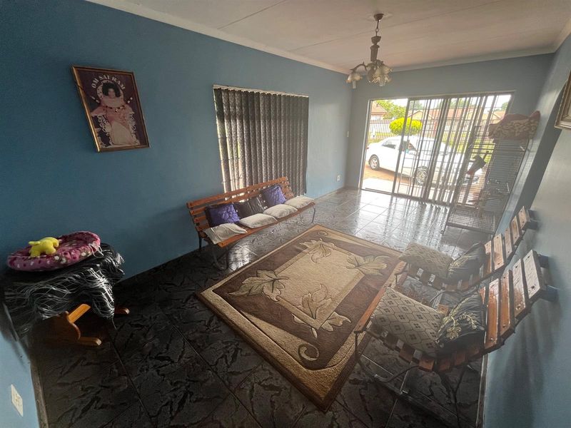 A living room featuring dark tiled flooring, blue painted walls, and sliding glass doors providing access to the exterior.