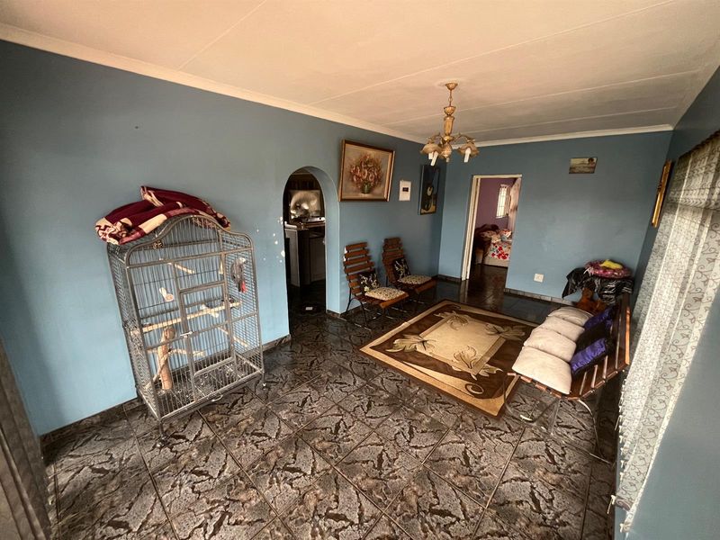 A living room featuring dark patterned floor tiles, blue walls, and an arched doorway leading to an adjacent space.