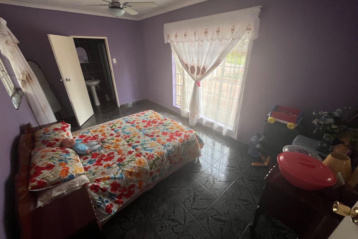 A bedroom featuring dark tiled flooring, a ceiling fan, and an en-suite bathroom access.