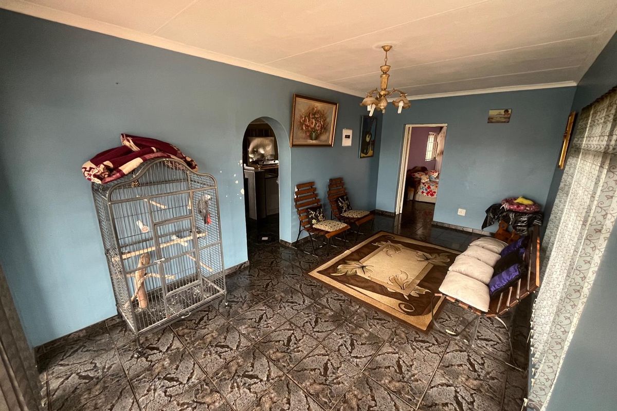 A living room featuring dark patterned floor tiles, blue walls, and an arched doorway leading to an adjacent space.