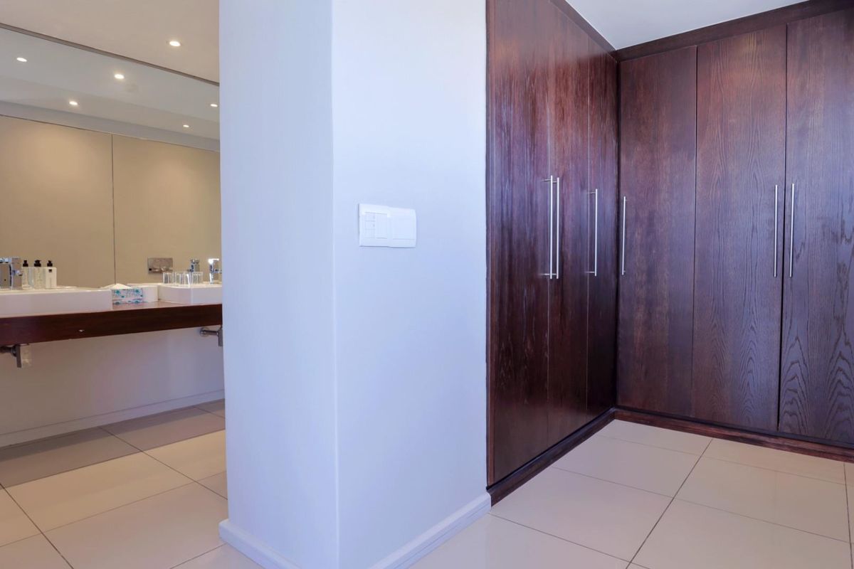 A modern bathroom featuring a double vanity with integrated sinks, large wall-mounted mirror, and extensive dark wood built-in cabinetry for storage.
