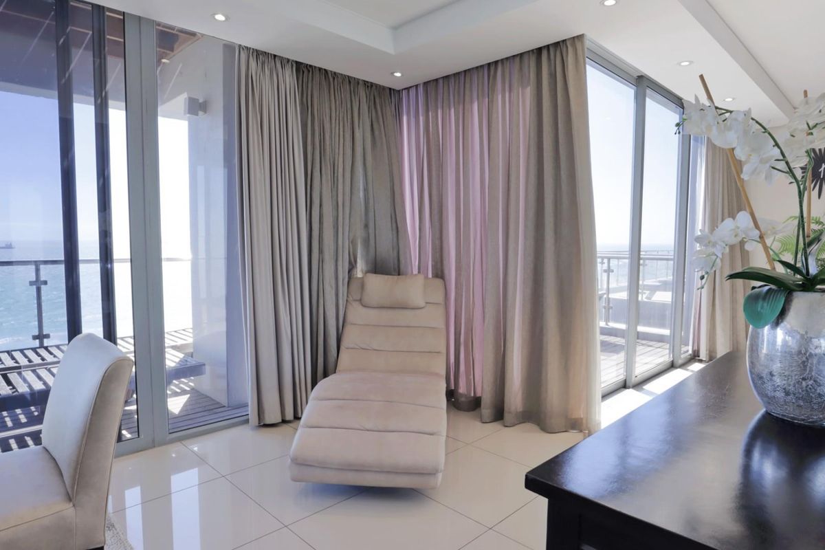 A bright bedroom featuring floor-to-ceiling glass sliding doors that open onto a private balcony with expansive ocean views.