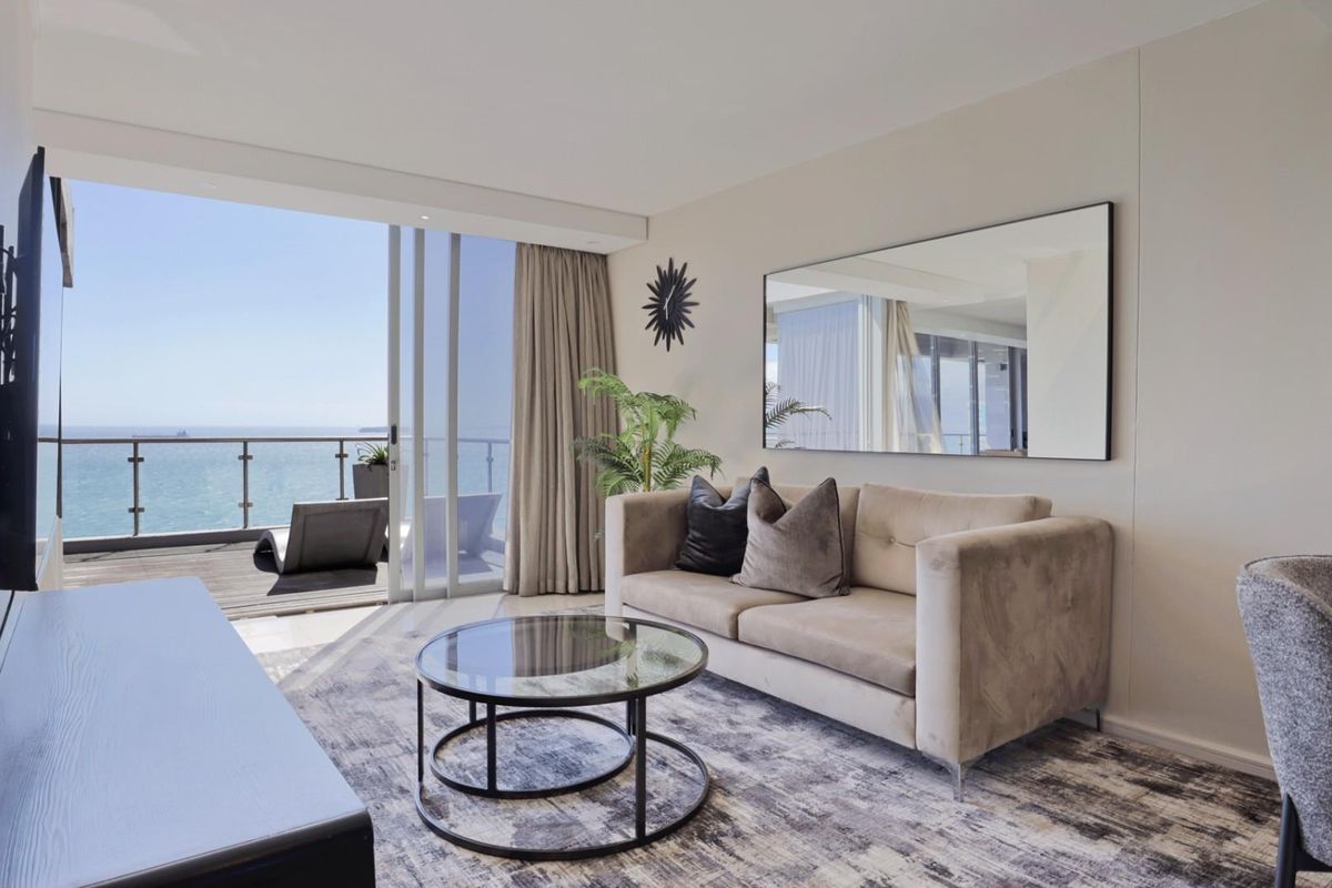 Modern living room featuring large sliding glass doors that open onto a balcony with expansive ocean views.