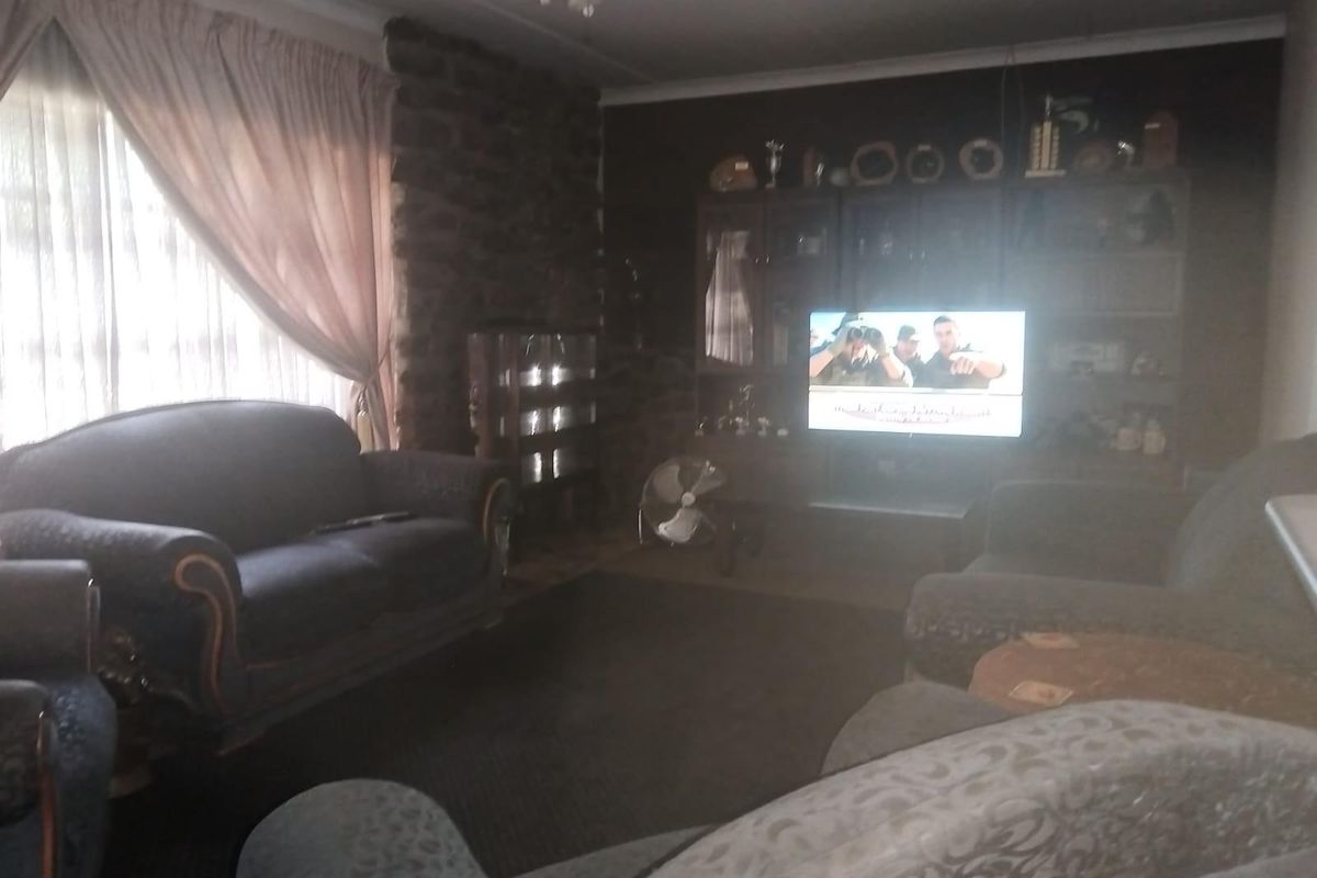 A living room featuring a prominent stone feature wall and dark interior finishes, providing a traditional layout with ample space for seating.