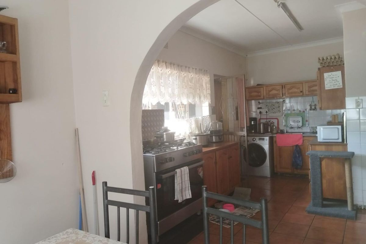 A functional kitchen featuring wooden cabinetry, a gas stove, and tiled flooring, connected to the dining area through a classic arched doorway.
