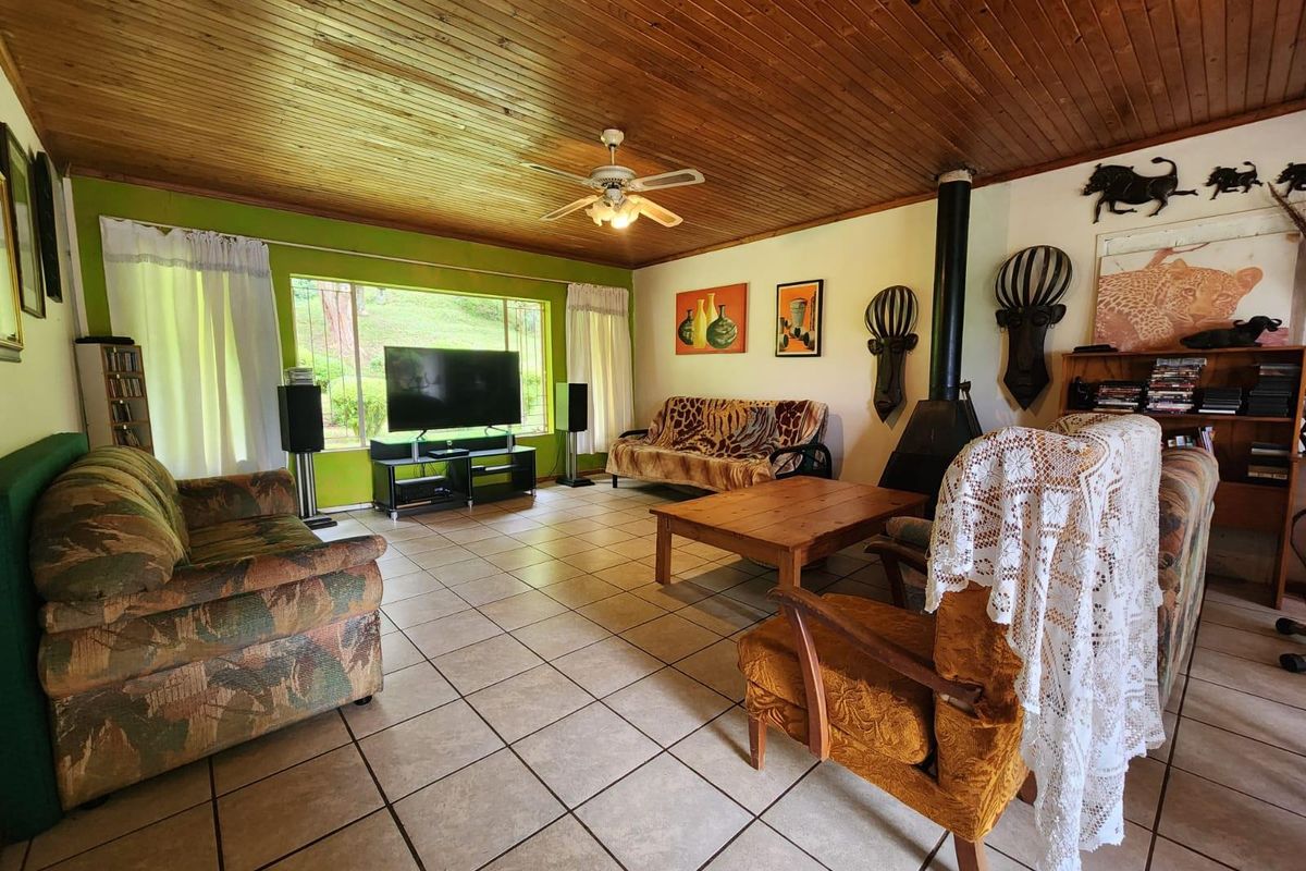 Spacious living room featuring a wood-burning fireplace, tiled flooring, and a timber-clad ceiling, offering a comfortable and functional family living space.