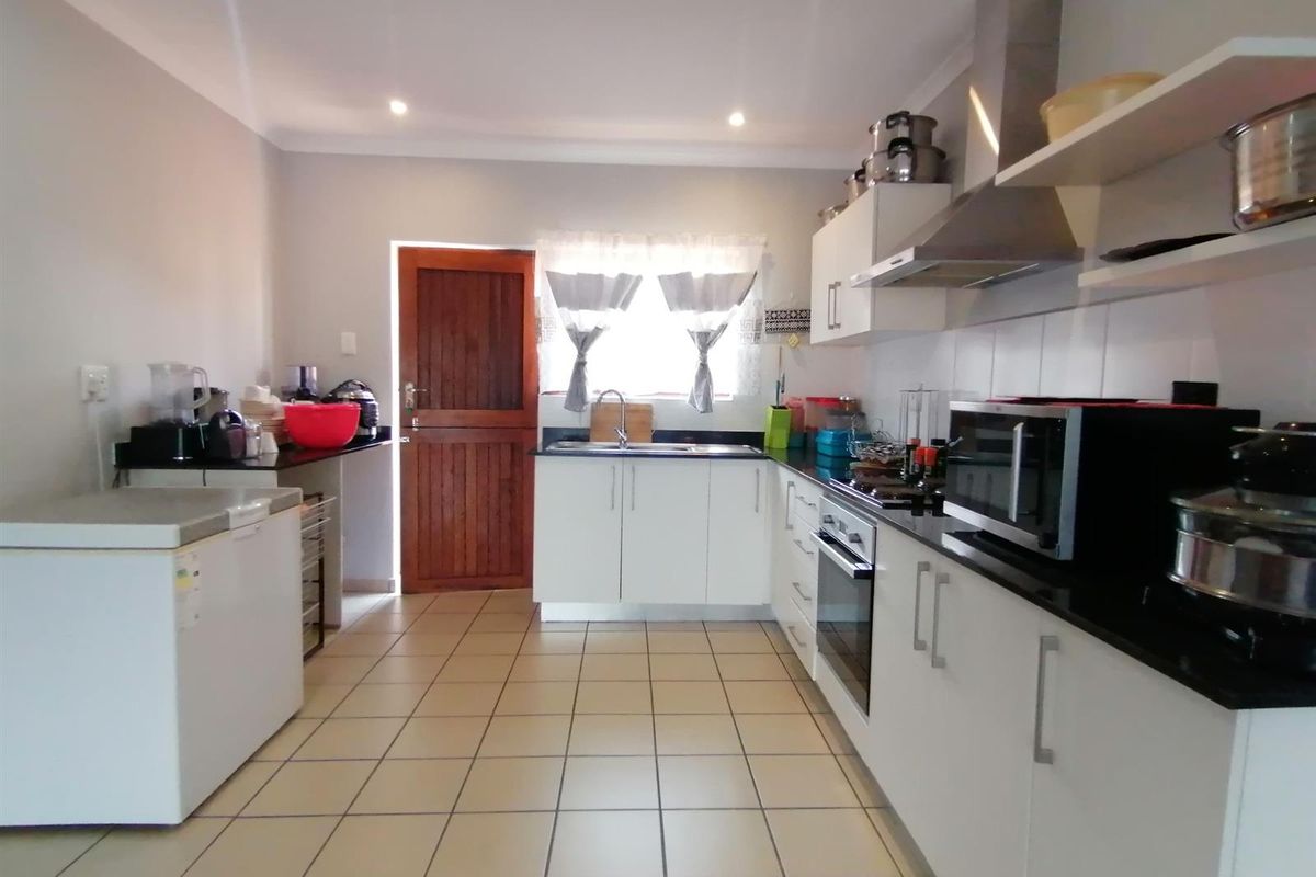A functional kitchen featuring white cabinetry, dark granite countertops, stainless steel appliances, and tiled flooring with direct access to an exterior door.