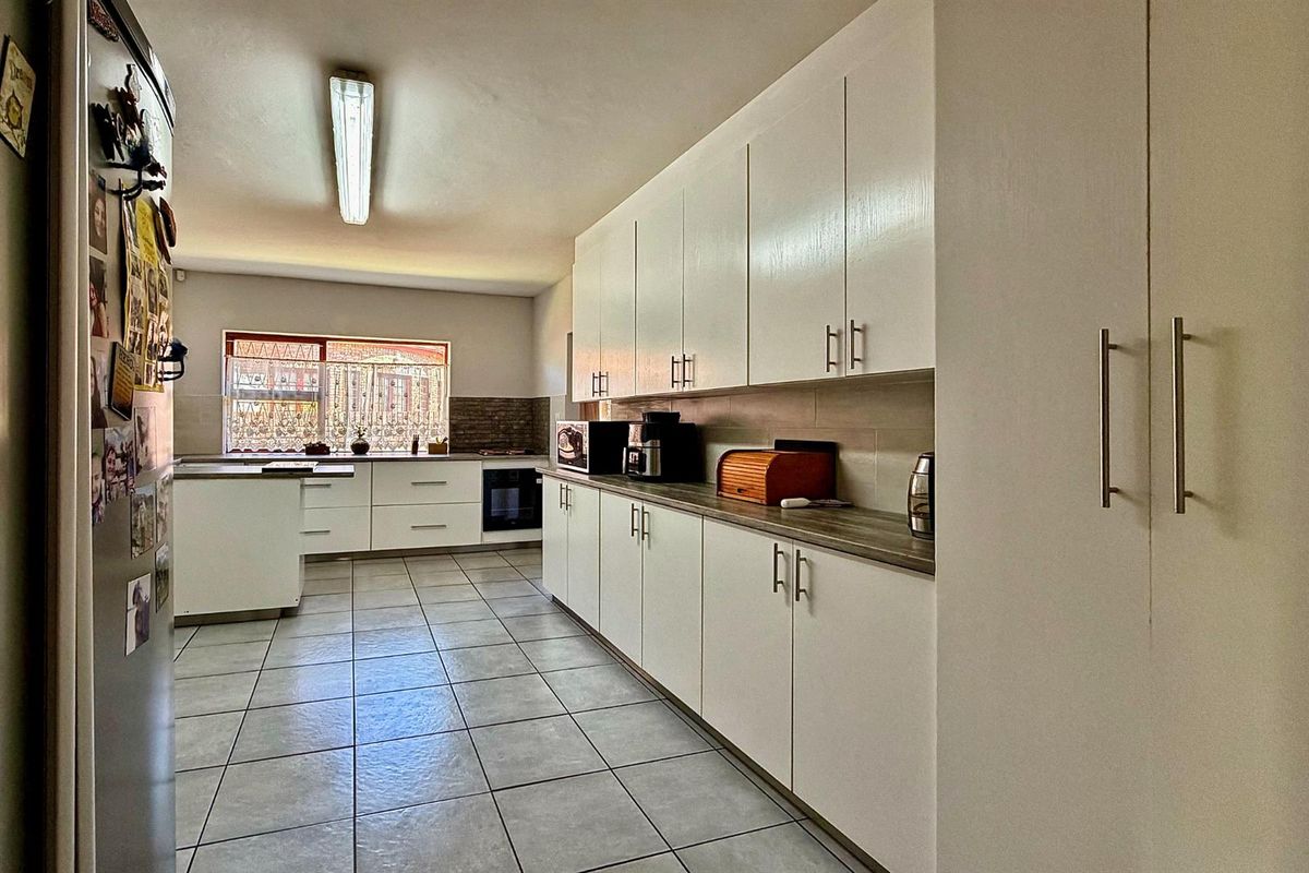A functional kitchen featuring white built-in cabinetry, laminate countertops, tiled flooring, and a built-in oven with a tiled backsplash.