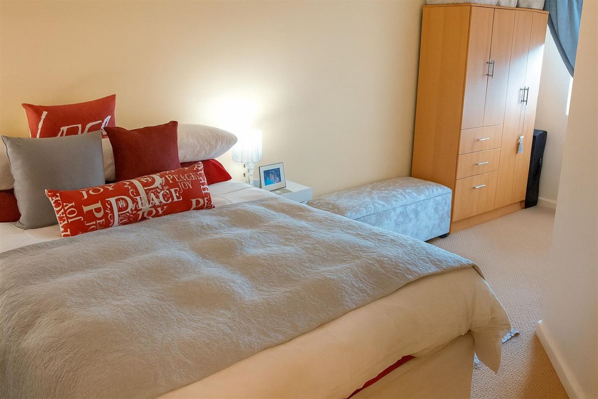 A bedroom featuring neutral carpeting and a built-in wooden wardrobe.