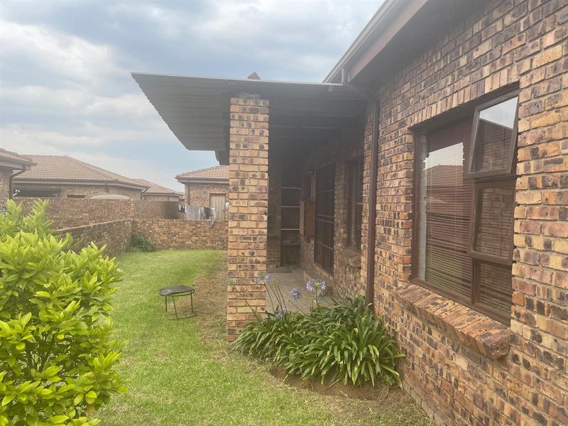 A covered brick patio area overlooking a private garden with a brick boundary wall and established landscaping.