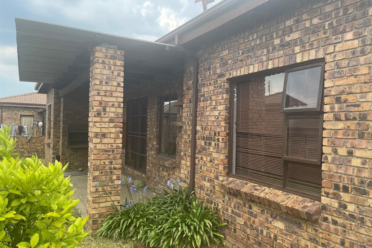 Rear exterior view of the penthouse featuring a face brick facade, a covered patio area with a built-in braai, and aluminium window frames.