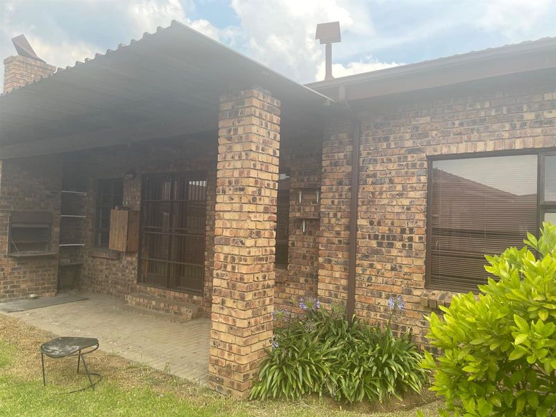Covered outdoor patio area featuring a built-in braai, brick pillars, and paved flooring, providing a functional space for outdoor entertaining.