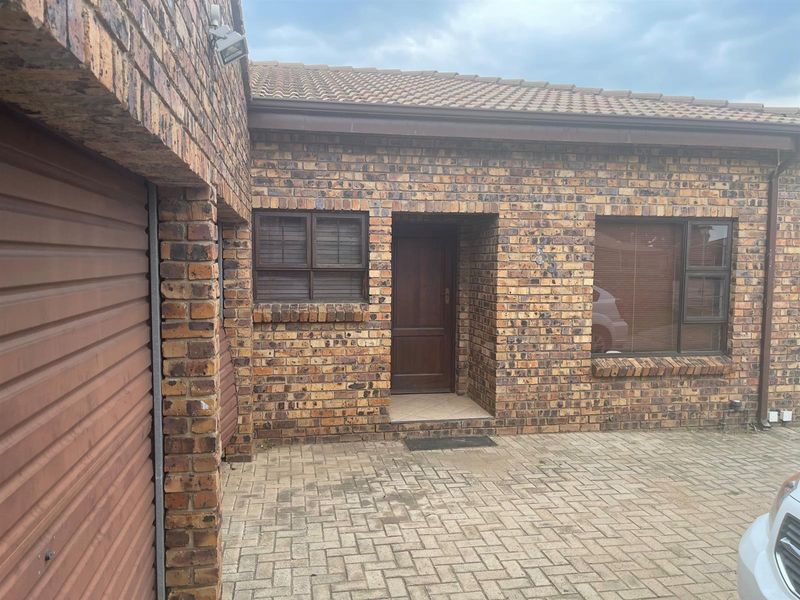 Front exterior view of a face brick penthouse unit featuring a paved driveway, garage access, and a covered entrance.