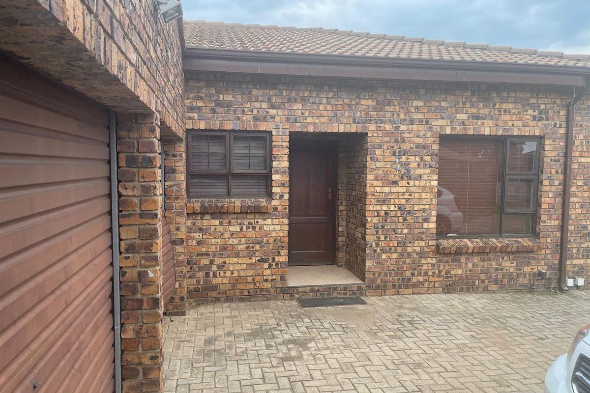 Front exterior view of a face brick penthouse unit featuring a paved driveway, garage access, and a covered entrance.