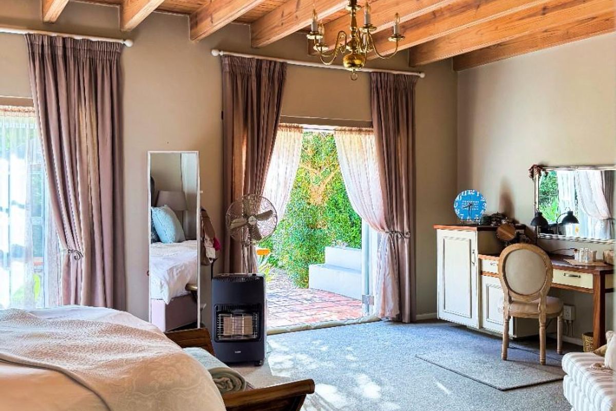 Spacious bedroom featuring exposed timber beam ceilings, carpeted flooring, and direct access to an outdoor patio area through glass doors.