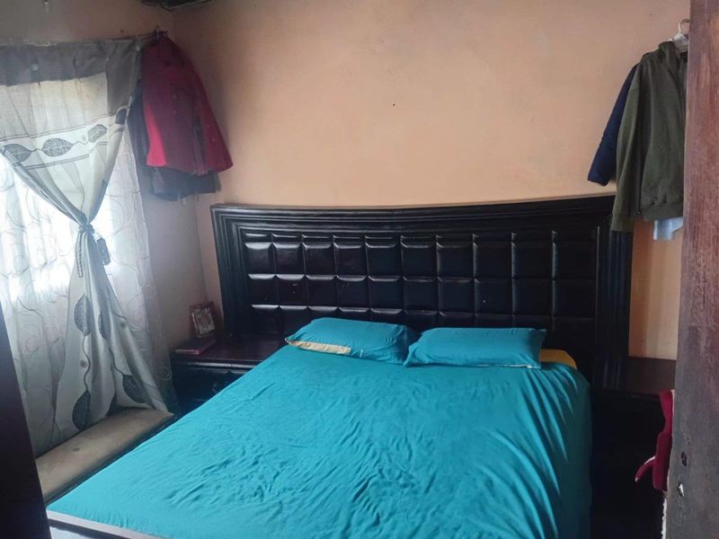 A bedroom featuring a built-in headboard and window with curtain fixtures.