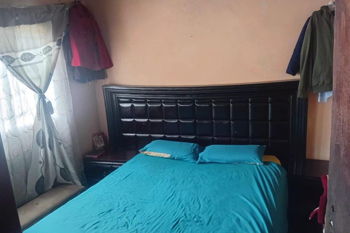 A bedroom featuring a built-in headboard and window with curtain fixtures.