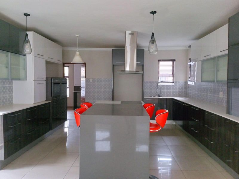 Modern kitchen featuring a central island, sleek cabinetry, built-in oven, stainless steel extractor fan, and tiled flooring.
