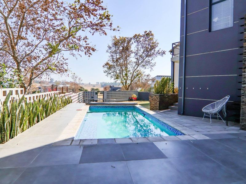A modern outdoor pool area featuring tiled decking, stone cladding accents, and a perimeter wall, offering a clean and well-maintained space for relaxation.