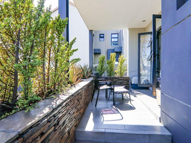 A covered patio area featuring stone-clad planter boxes, tiled flooring, and direct access to the interior through glass doors.