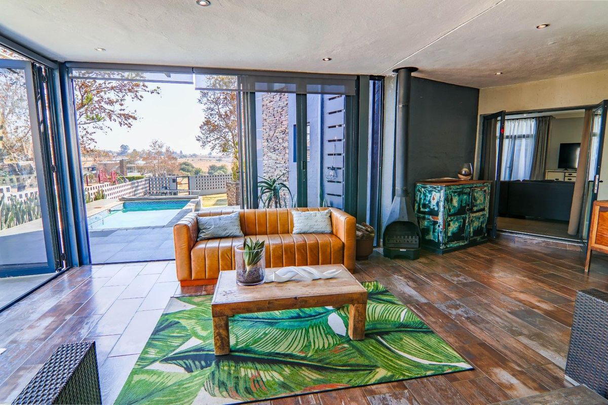 Spacious living area featuring wood-look tile flooring, a modern freestanding fireplace, and large sliding glass doors opening to a pool deck.