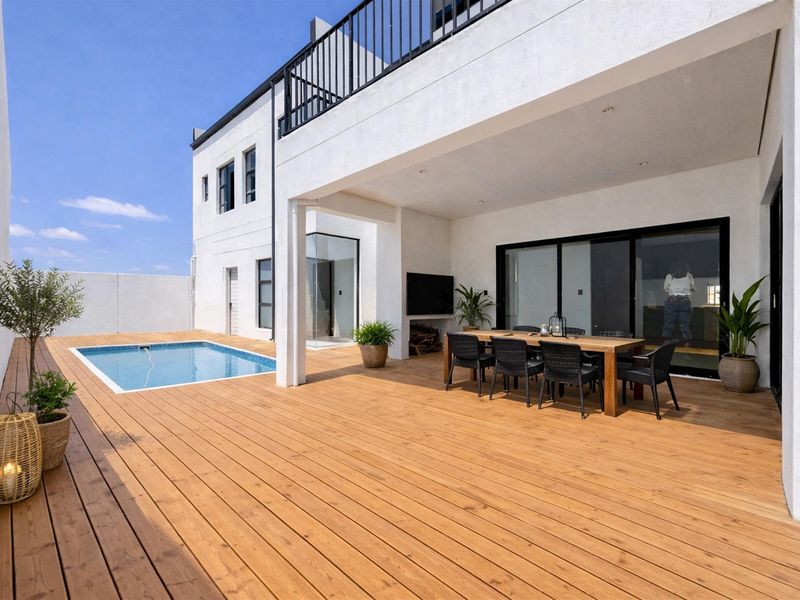 Spacious covered patio featuring timber decking, a built-in fireplace, and direct access to a private swimming pool and the main residence.