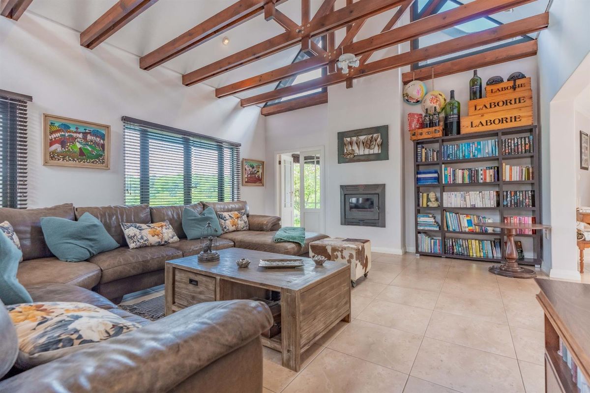 Spacious living room featuring high vaulted ceilings with exposed timber beams, tiled flooring, and a built-in fireplace, creating a warm and inviting atmosphere.