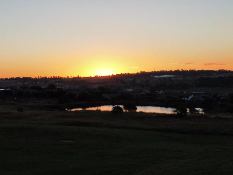 A scenic sunset view overlooking a natural landscape with a small pond and distant horizon.