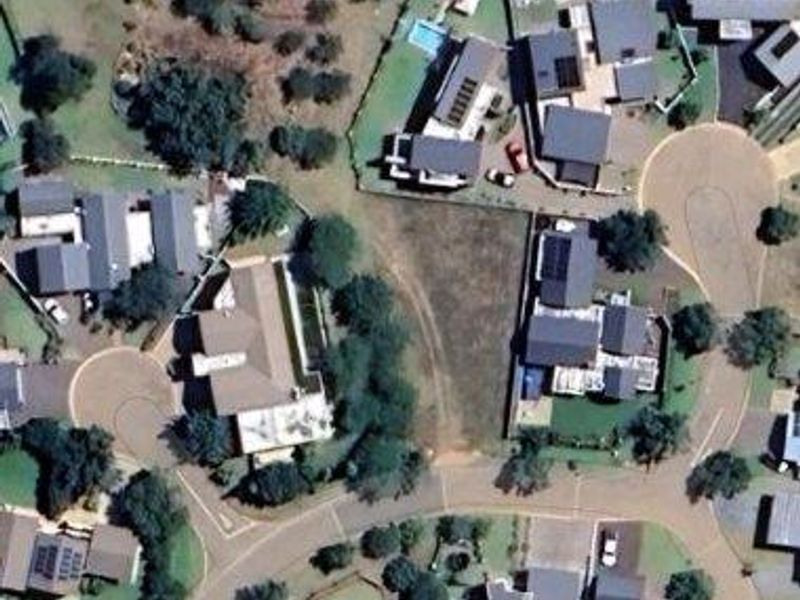 Aerial view of a vacant residential plot situated within an established suburban estate, surrounded by existing residential properties.
