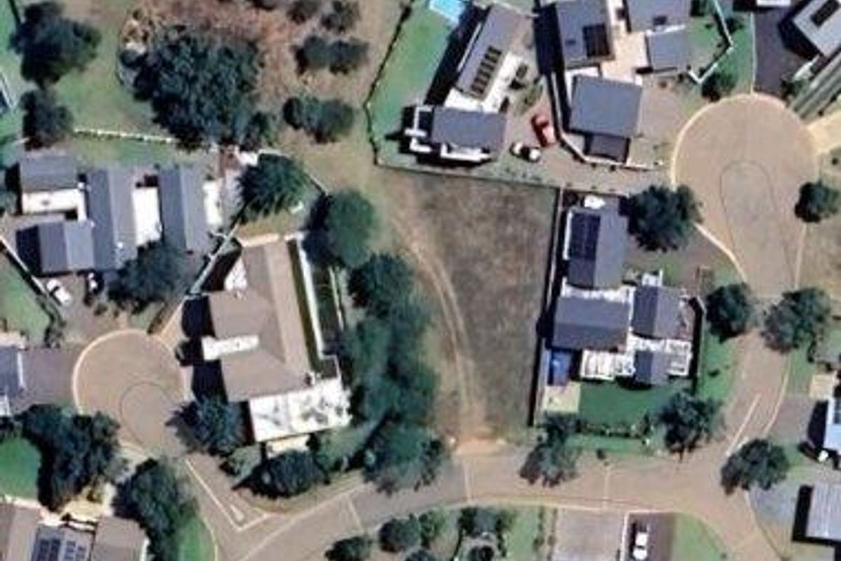 Aerial view of a vacant residential plot situated within an established suburban estate, surrounded by existing residential properties.