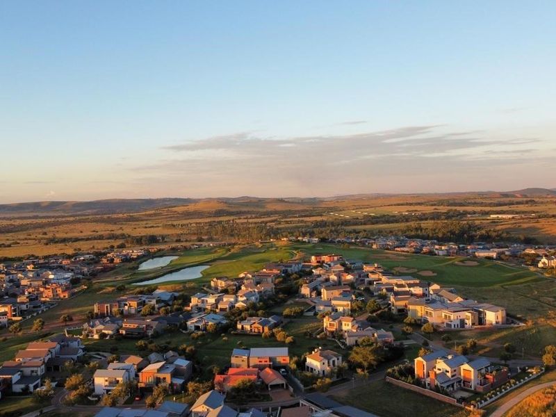 An expansive aerial view of a residential estate integrated with a golf course, showcasing the surrounding landscape and community layout.