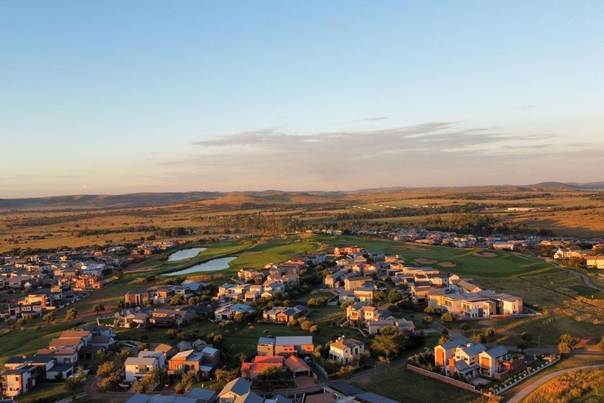 An expansive aerial view of a residential estate integrated with a golf course, showcasing the surrounding landscape and community layout.