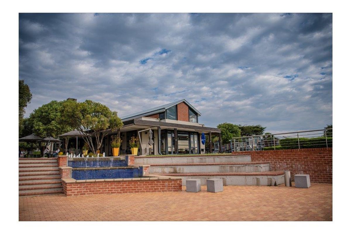 A well-maintained rear exterior area featuring a paved terrace, tiered brick retaining walls, and a decorative water feature leading to the main building structure.