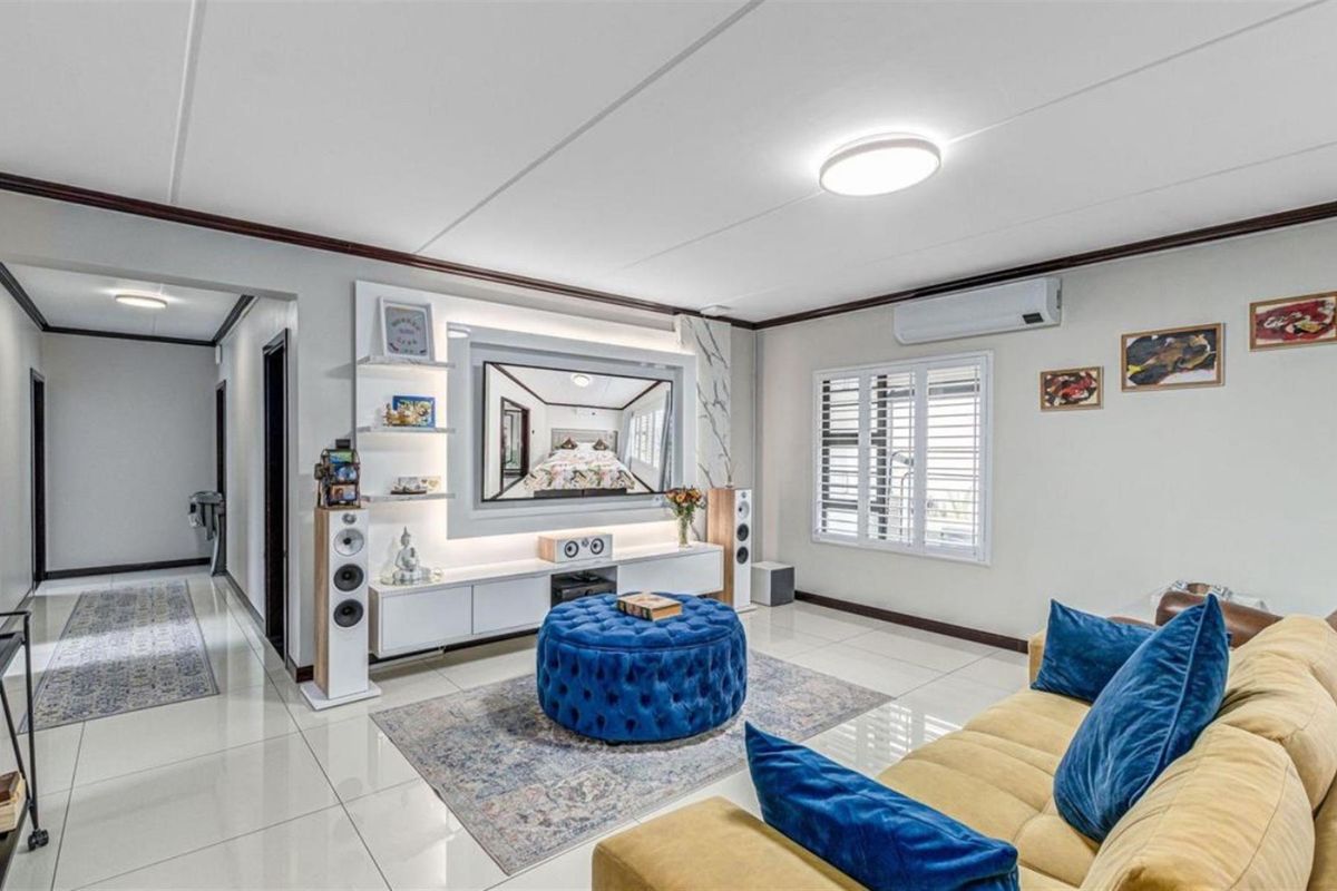 Modern living room featuring a custom built-in media unit with integrated lighting, tiled flooring, and a wall-mounted air conditioning unit.