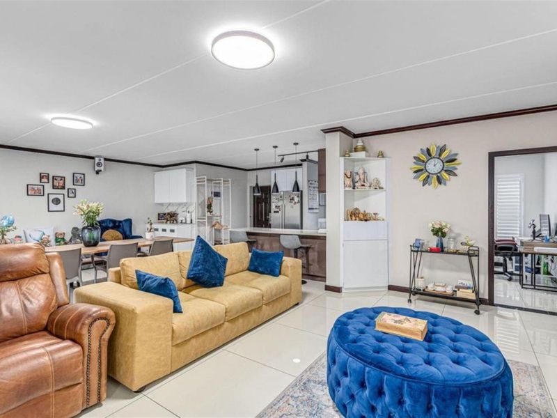 Spacious open-plan living and dining area featuring tiled flooring, built-in shelving, and a modern kitchen island with pendant lighting.