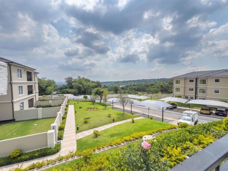 Elevated view of the apartment complex grounds featuring landscaped gardens, paved walkways, and covered parking bays.