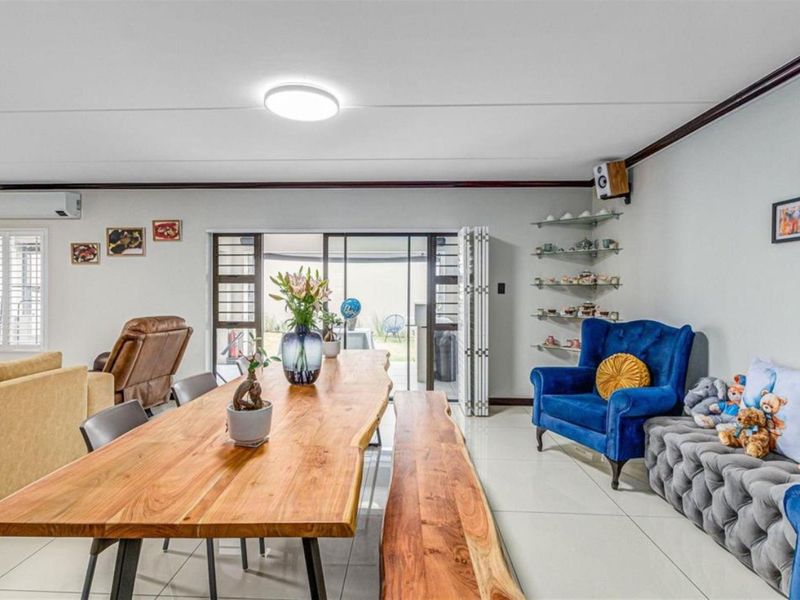 Spacious open-plan living and dining area featuring tiled flooring, air conditioning, and large sliding glass doors providing access to the outdoor space.