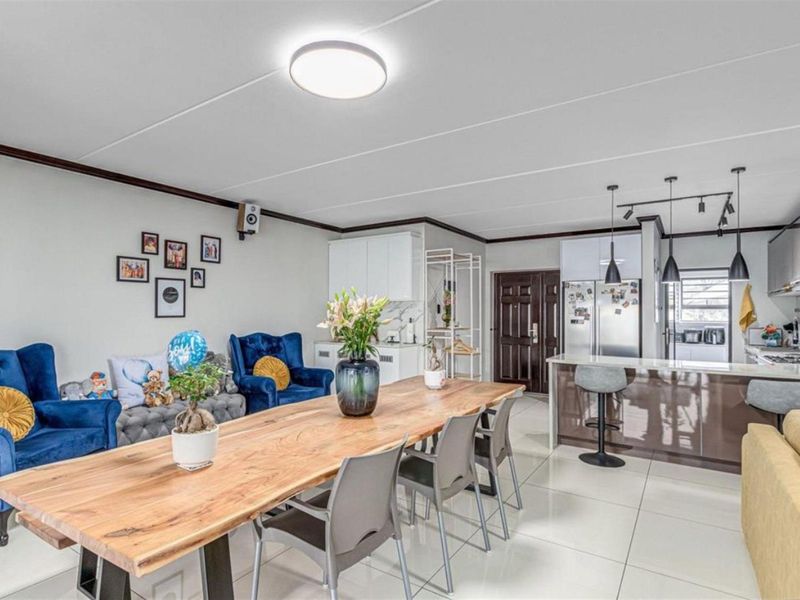 Spacious open-plan living and dining area featuring modern tiled flooring, a central kitchen island, and integrated cabinetry, creating a functional and cohesive living space.