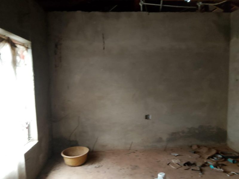 An unfinished room featuring exposed concrete walls and ceiling, requiring significant renovation and finishing work to become a habitable living space.