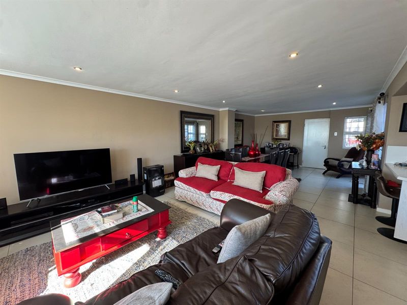 Spacious open-plan living and dining area featuring neutral tiled flooring, recessed downlighting, and a seamless flow between the lounge and kitchen space.