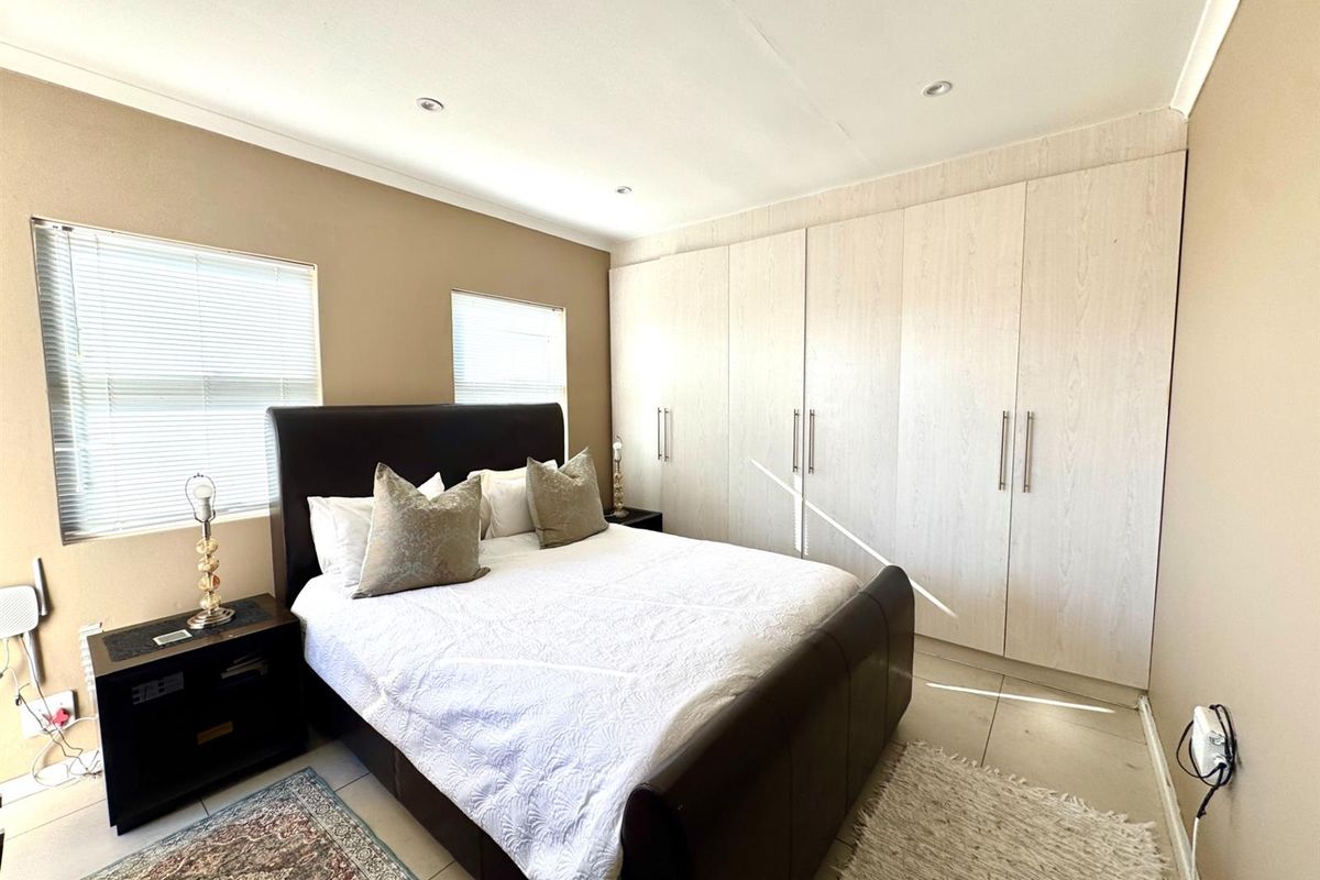 A well-maintained bedroom featuring built-in floor-to-ceiling wardrobes, tiled flooring, and recessed ceiling lighting.