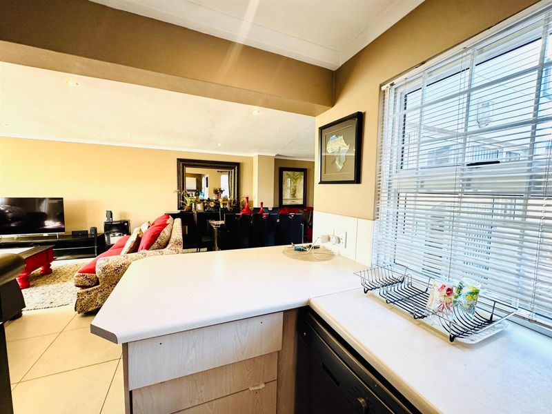 Open-plan kitchen area featuring a breakfast counter, integrated cabinetry, and tiled flooring, seamlessly flowing into the adjacent living and dining space.