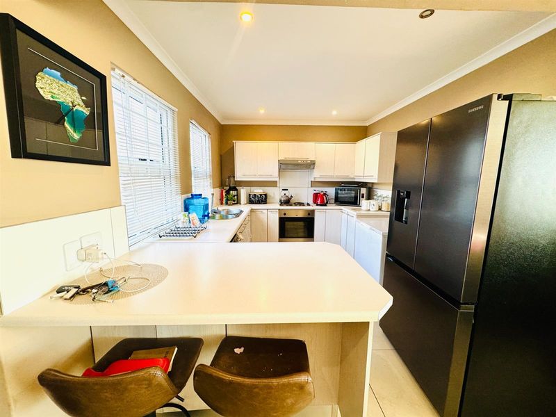 A functional kitchen featuring light-toned cabinetry, a built-in oven, extractor fan, and a breakfast bar counter, providing a practical workspace.