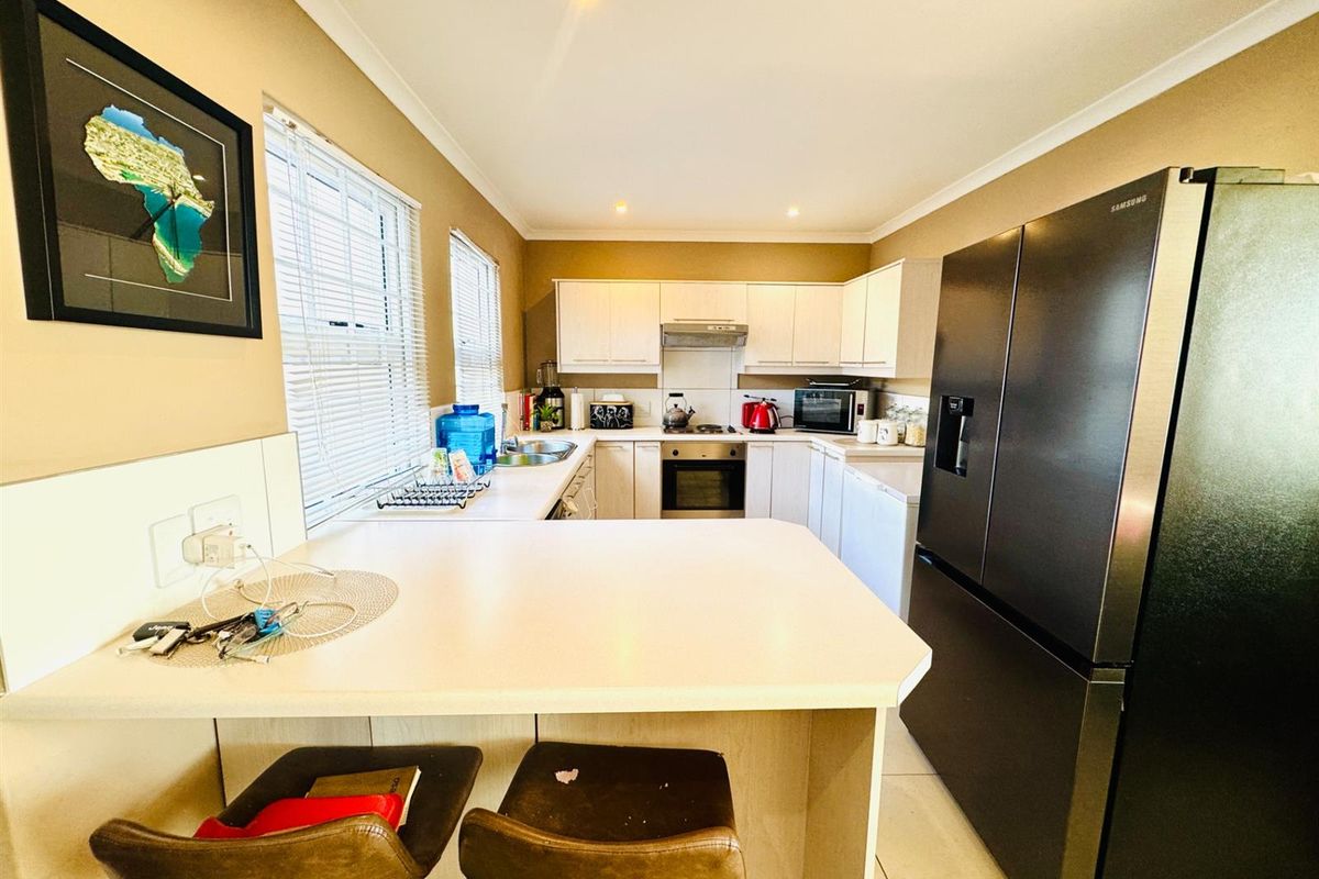 A functional kitchen featuring light-toned cabinetry, a built-in oven, extractor fan, and a breakfast bar counter, providing a practical workspace.