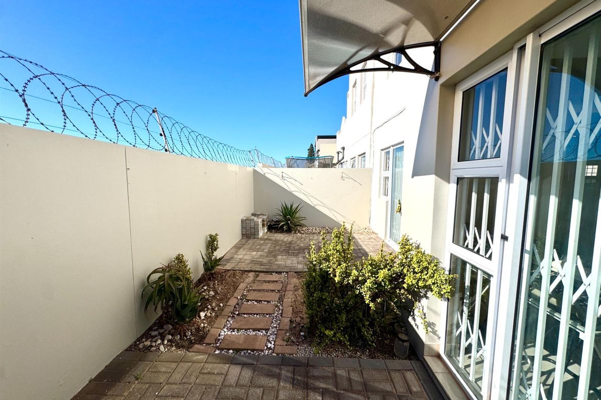 A private rear courtyard featuring paved areas, a built-in braai, and secure perimeter walling with razor wire.